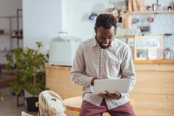 Masada oturan ve dizüstü bilgisayarda çalışma neşeli adam
