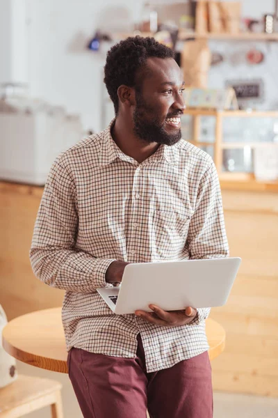 Masanın üzerine eğilerek ve dizüstü tutan çekici adam