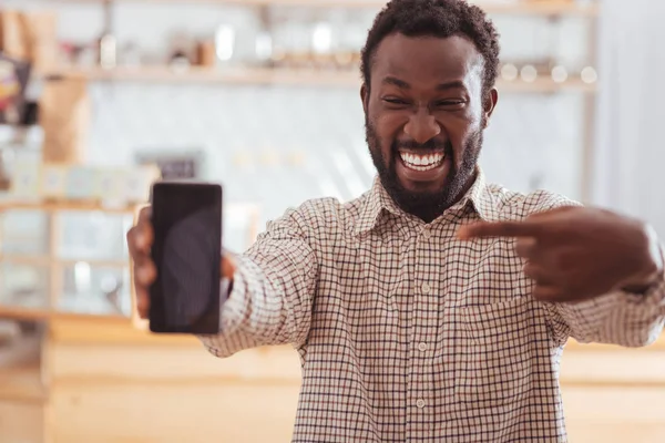 Šťastný muž ukázal na svůj telefon v kavárně — Stock fotografie
