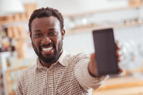 Joyful man showing his new phone in coffeehouse