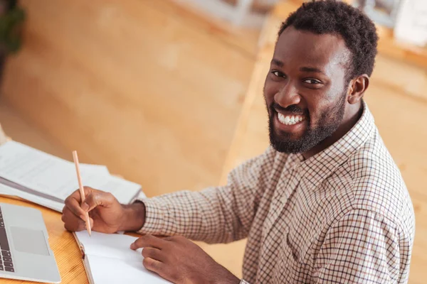 Happy man posing while writing in notebook — Stock Photo, Image