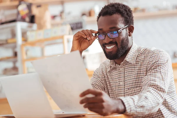 Cheerful man looking through research results in cafe