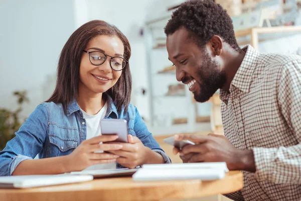 Femme agréable montrant son collègue poste drôle au téléphone — Photo