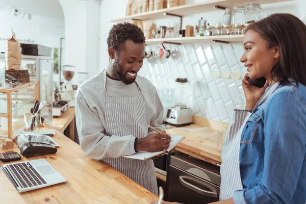 Barista sonriente poniendo orden hecha por teléfono —  Fotos de Stock