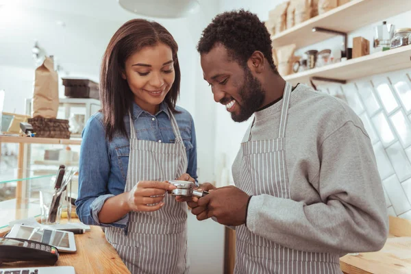 Agréables baristas souriants scrutant portafilter — Photo