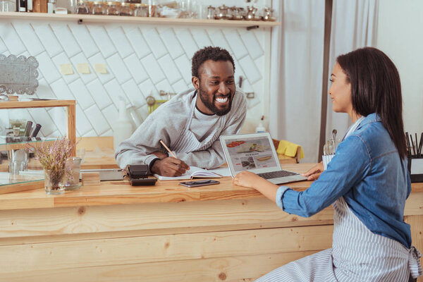 Pleasant woman talking about cafes website with barista
