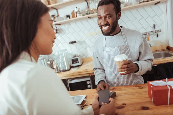 Mulher agradável usando a tecnologia NFC para pagar no café — Fotografia de Stock