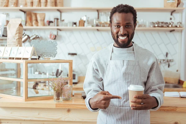 Charmoso barista apontando para xícara de café — Fotografia de Stock