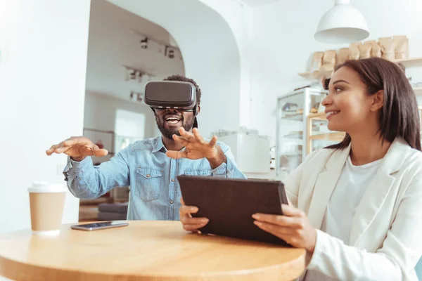 Mujer sonriente viendo a su amigo probar los auriculares VR — Foto de Stock