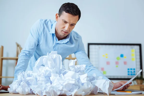 Verward kantoor werknemer kijken verfrommeld papier — Stockfoto