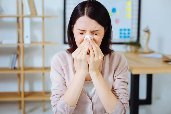 Ill female person sneezing at work — Stock Photo, Image
