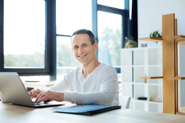 Fröhlicher positiver Geschäftsmann, der seine Arbeit genießt — Stockfoto