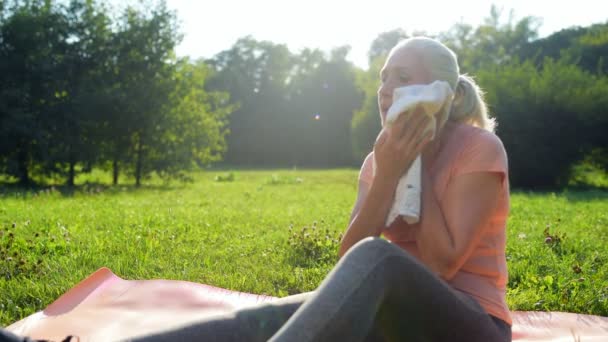 Женщина отдыхает после спортивных упражнений в парке — стоковое видео