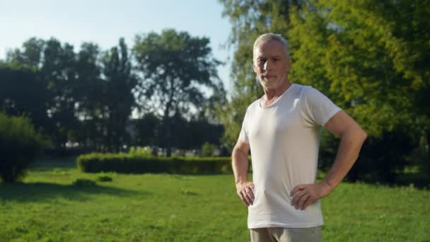 Sportif yaşlı adam parkta ayakta — Stok video