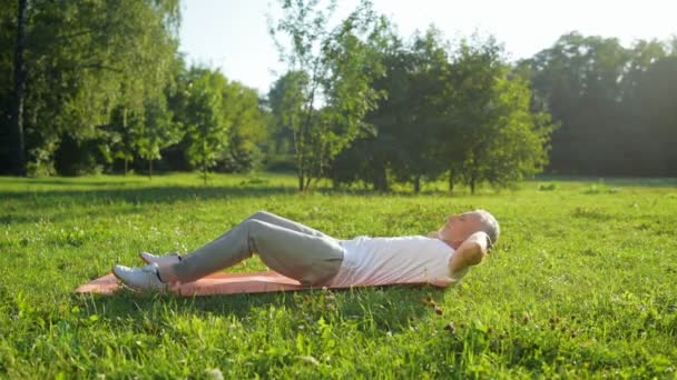 Man doing abdominal crunches outdoors — Stock Video