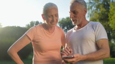 Parkta telefonlarını kullanarak neşeli yaşlı çift