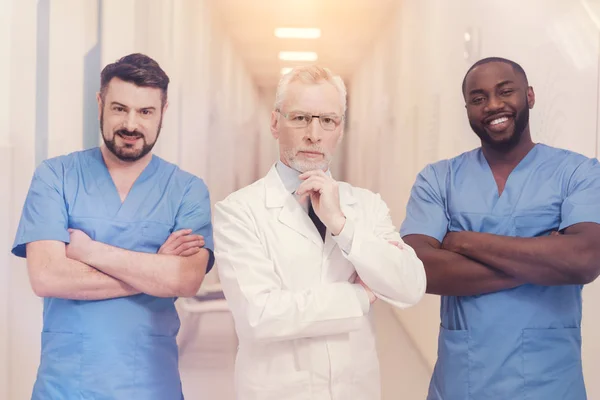 Seriöser Professor steht zwischen zwei Medizinstudenten — Stockfoto