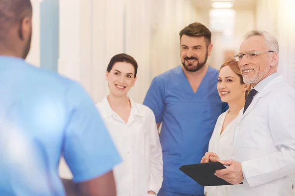 Groupe de travailleurs médicaux souriants qui regardent leur stagiaire — Photo