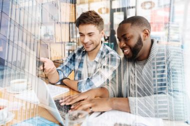 Bir dizüstü bilgisayar kullanan heyecanlı öğrenciler