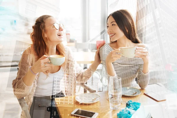 Улыбающиеся девушки веселятся в кафе — стоковое фото