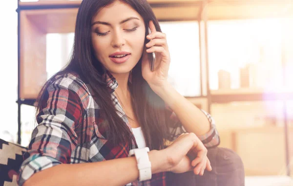 Occupé jeune dame vérifier l'heure tout en parlant au téléphone — Photo