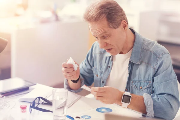 Sick adult man reading the instructions on the medicines — Stock Photo, Image