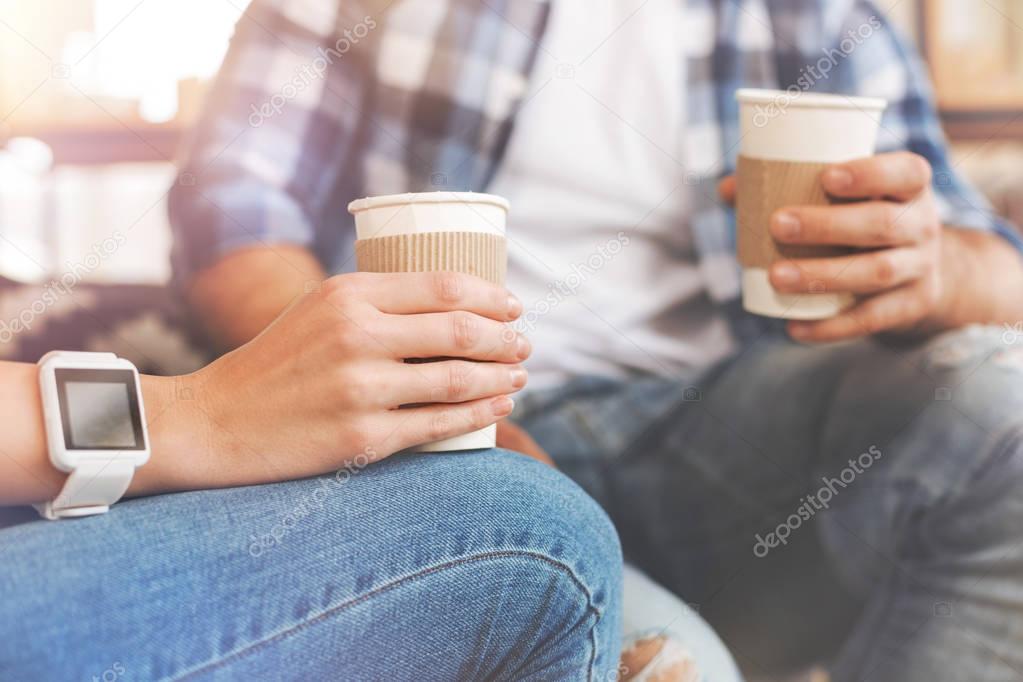Close up of two friends drinking take away coffee