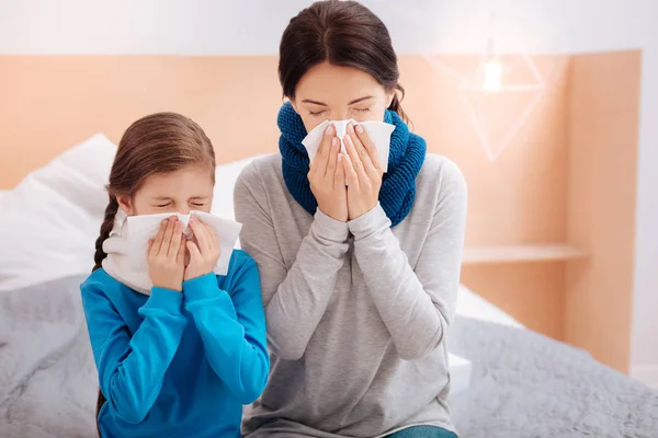 Ill mother and daughter sneezing together — Stock Photo, Image