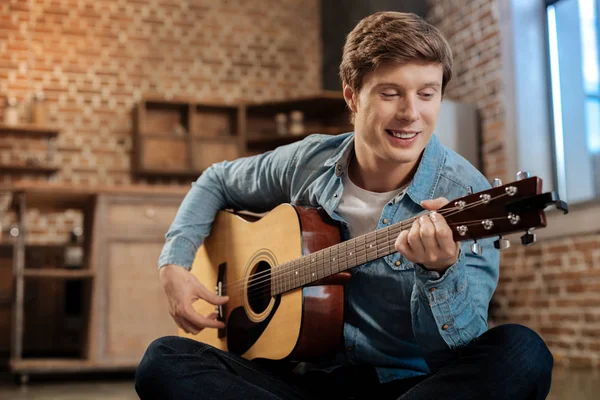 Jovem alegre tocando guitarra e sorrindo — Fotografia de Stock