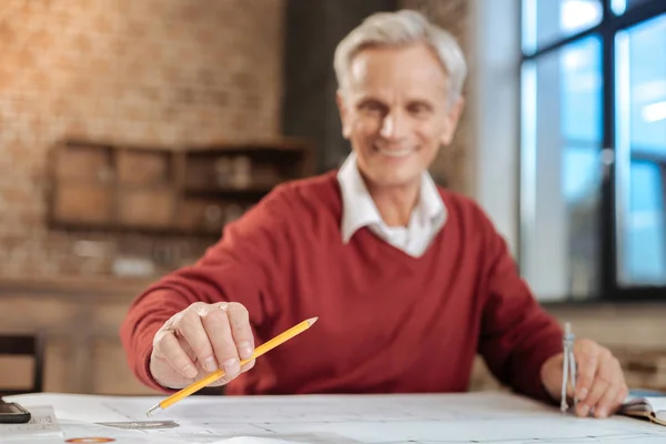 Lachende ingenieur potlood nemen tijdens het werken aan blauwdruk — Stockfoto