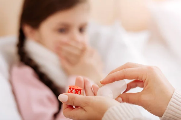 Botella pequeña con pastillas necesarias en las manos de una mujer cariñosa — Foto de Stock