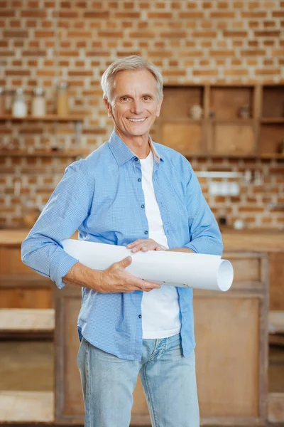 Grijs-haired ingenieur poseren met een blauwdruk — Stockfoto