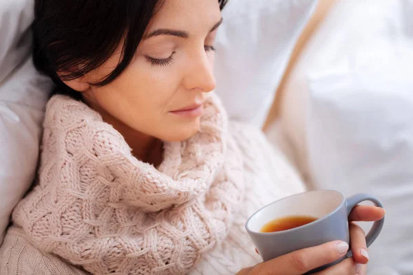Mujer enferma bebiendo té caliente con los ojos cerrados — Foto de Stock