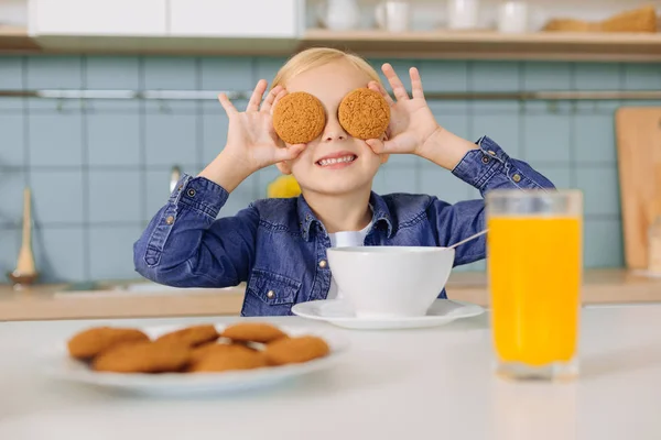 幸せの素敵な女の子が彼女の目にクッキーを置くこと — ストック写真