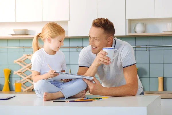 Hombre guapo positivo preguntando a su hija sobre la tarea hogareña — Foto de Stock