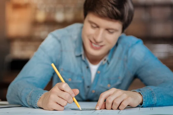 Smiling man using a protractor while drawing blueprint — Stock Photo, Image