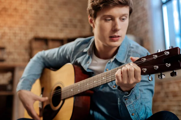 Angenehmer junger Mann spielt zu Hause Gitarre — Stockfoto