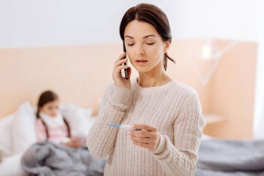Sakin kadınla ciddi bir telefon termometre görünümlü