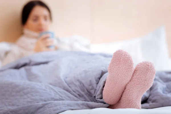 Varme lyserøde sokker af en syg ung kvinde - Stock-foto