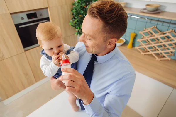 Glad trevlig man ger en flaska med mjölk till dottern baby — Stockfoto