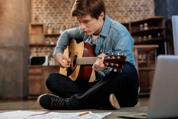 Gutaussehender Mann übt Gitarre auf dem Boden — Stockfoto