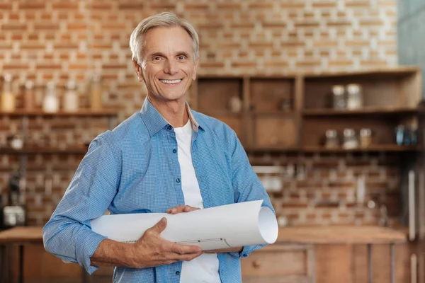 Grijs-haired senior ingenieur holding een blauwdruk en glimlachen — Stockfoto