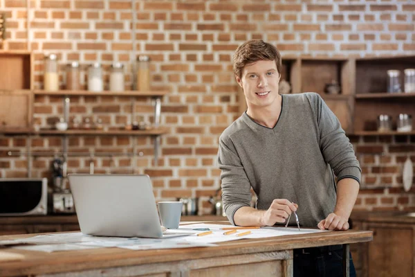 Joven agradable sosteniendo una brújula y sonriendo — Foto de Stock