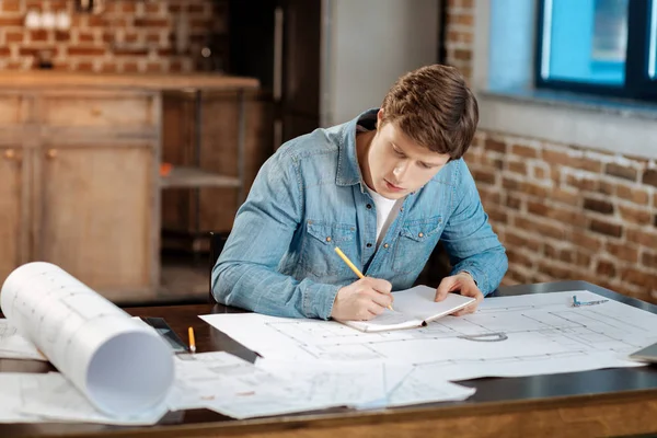 Jeune ingénieur prenant des notes concernant son projet — Photo