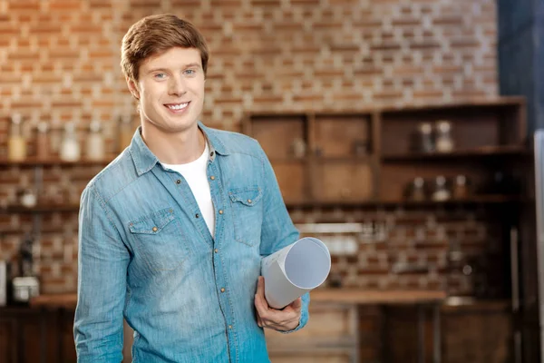 Handsome man posing with a rolled blueprint — Stock Photo, Image