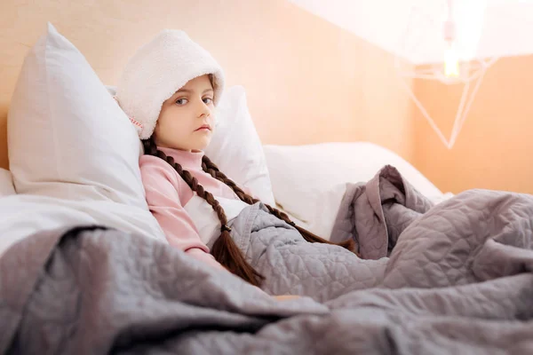 Gadis kecil tampak lelah saat sedang ditutupi dengan selimut lembut — Stok Foto