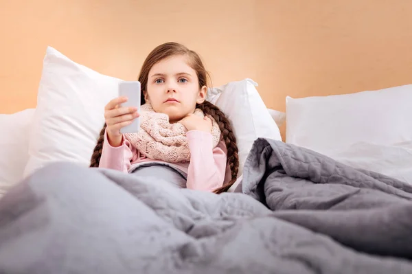 Niño sin emociones viendo la televisión mientras está en la cama —  Fotos de Stock