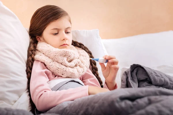 Chore dziecko uważnie ogląda termometr — Zdjęcie stockowe