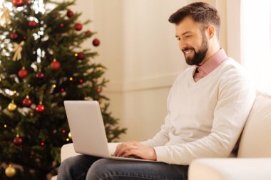 Noel ağacı ile odada dizüstü bilgisayarda çalışan yakışıklı adam