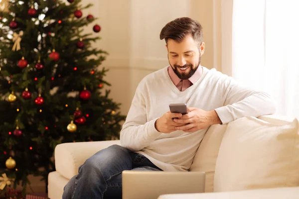 Vrolijke man zit op de Bank en SMS — Stockfoto